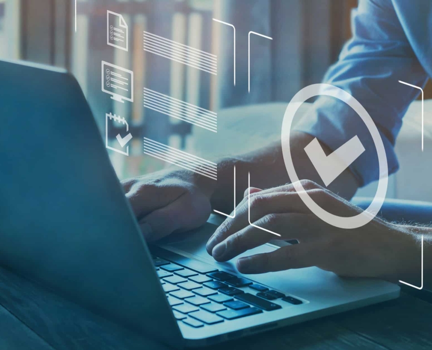 Person-sitting-at-desk-looking-over-compliance-documents-on-computer