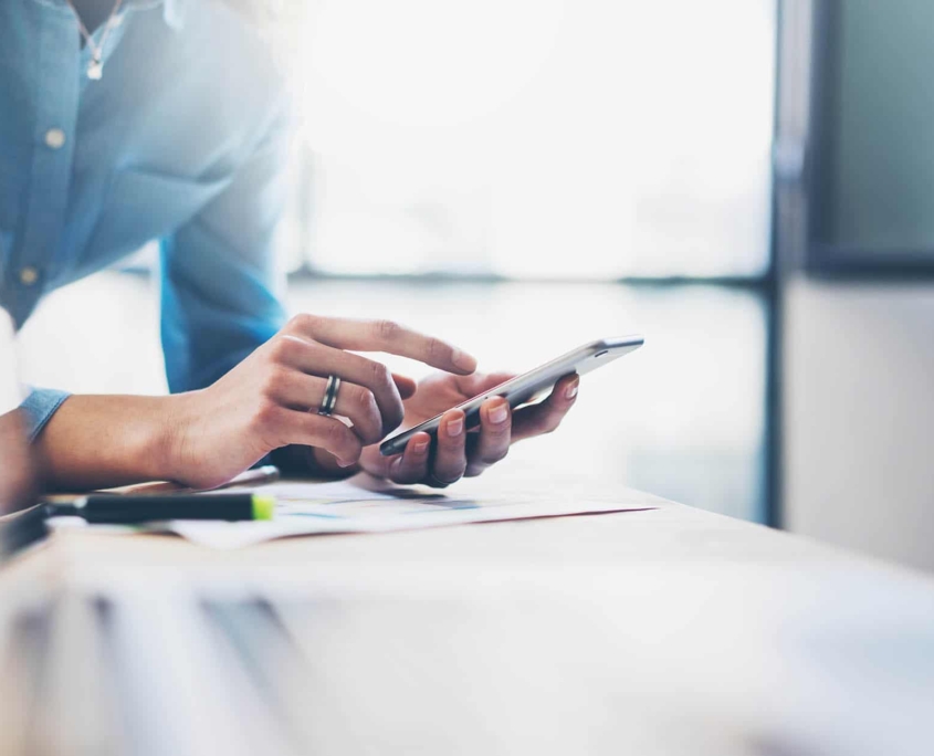 Person-using-their-phone-while-at-their-desk