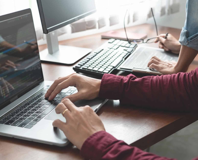 Side-view-of-two-people-working-on-computers