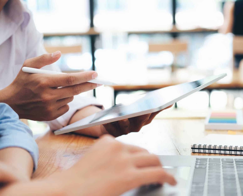 Side-view-of-two-office-workers-looking-at-tablet