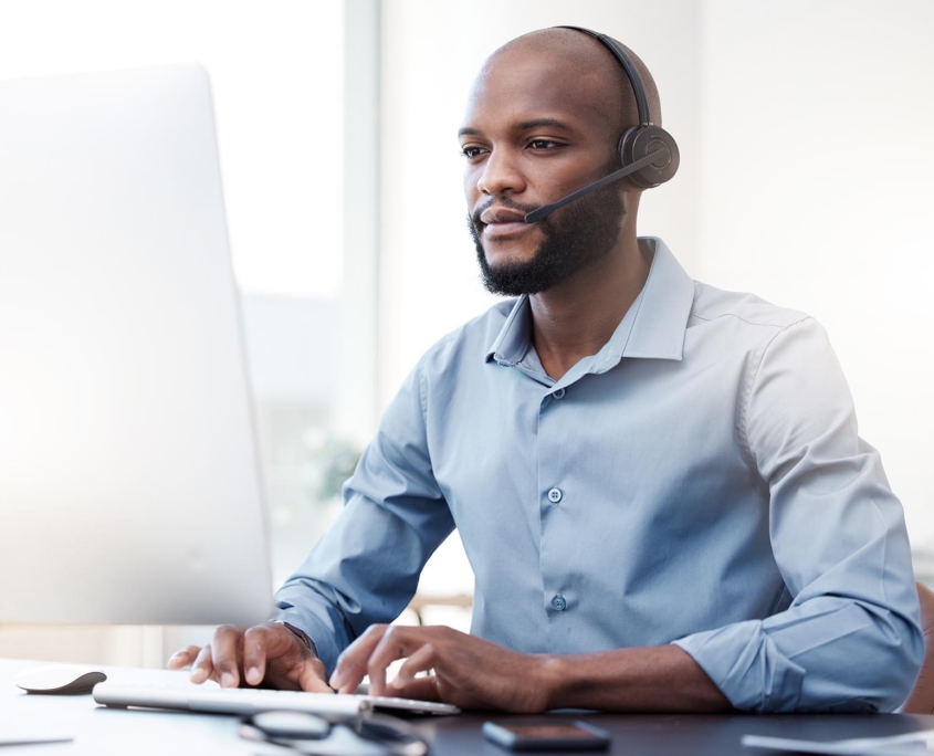 Side view of a man with a headset working on a computer