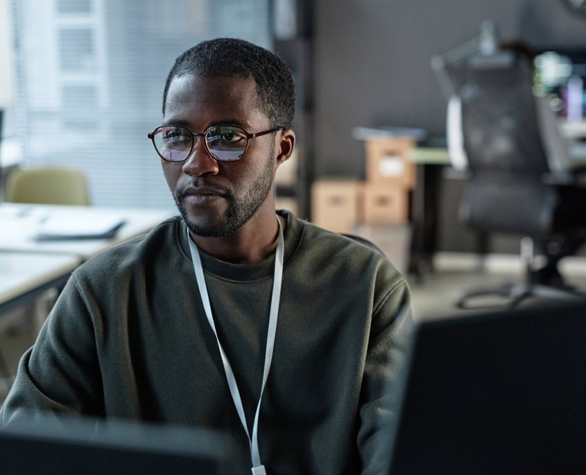 Minimal portrait of focused man using computer in IT development office with code lines reflection in glasses