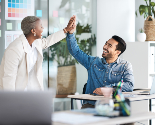 Two peope in offce high-fiving